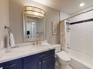 Full bathroom featuring vanity, shower / bath combination with curtain, and toilet