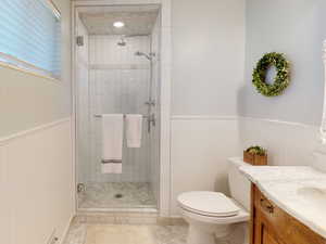 Bathroom with tile patterned flooring, vanity, toilet, and an enclosed shower