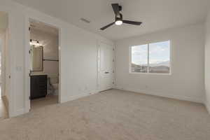 Unfurnished bedroom with connected bathroom, light colored carpet, a ceiling fan, baseboards, and visible vents