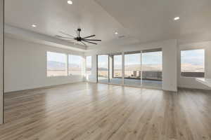 Interior space with baseboards, light wood-style floors, a mountain view, and a ceiling fan