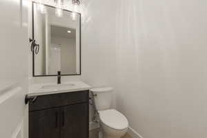 Half bath with vanity, toilet, and baseboards