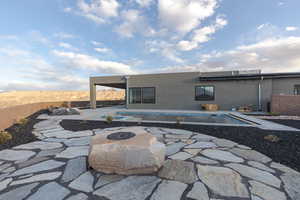 Rear view of house featuring an outdoor fire pit, fence, a fenced in pool, stucco siding, and a patio area