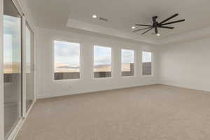 Spare room with a tray ceiling, recessed lighting, visible vents, light carpet, and baseboards