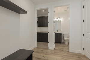 Bathroom featuring toilet, wood finished floors, vanity, and baseboards