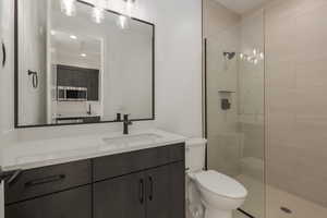 Bathroom featuring toilet, a walk in shower, and vanity