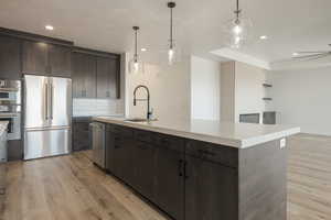 Kitchen featuring a center island with sink, appliances with stainless steel finishes, and light countertops