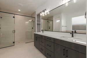 Bathroom featuring a stall shower, a sink, and double vanity