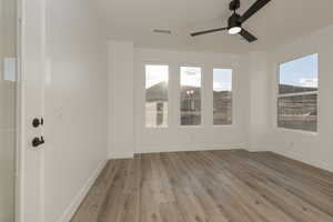 Unfurnished room featuring a ceiling fan, baseboards, visible vents, and light wood finished floors