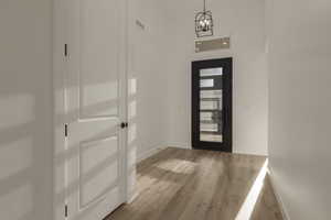 Foyer entrance with light wood-type flooring, an inviting chandelier, and baseboards