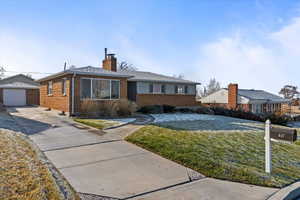 Single story home featuring a garage, and a healthy front lawn