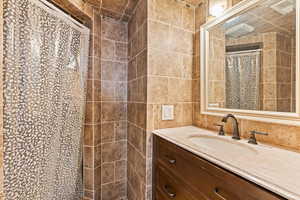 Bathroom with vanity, walk in shower, and tile walls - ensuite off of basement bedroom. Could be used as primary suite.