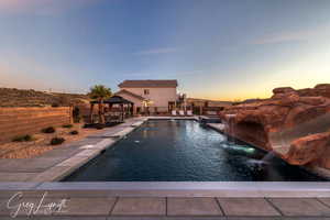 Pool at dusk featuring a gazebo, a patio, and pool water feature