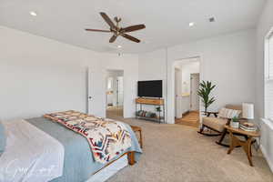 Bedroom featuring ensuite bath, ceiling fan, and light colored carpet