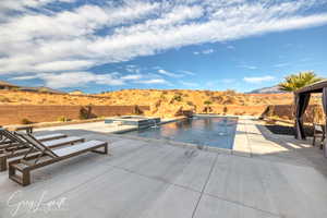 View of pool with pool water feature, a mountain view, a patio area, and an in ground hot tub