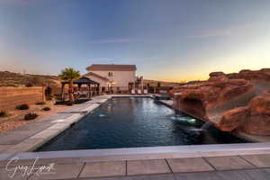 Pool at dusk featuring a gazebo, pool water feature, and a patio