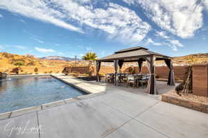 View of pool featuring a mountain view, a gazebo, pool water feature, and a patio area