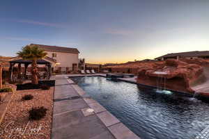 Pool at dusk featuring a gazebo, pool water feature, and a patio