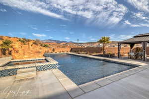 View of pool featuring an in ground hot tub, pool water feature, a gazebo, a patio area, and a mountain view