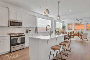 Kitchen with white cabinets, sink, stainless steel appliances, and a kitchen island with sink