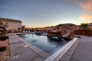 Pool at dusk featuring pool water feature