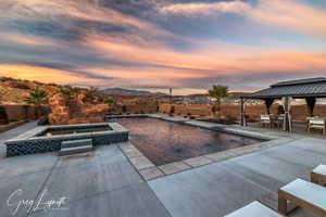 Pool at dusk featuring a gazebo, a mountain view, an in ground hot tub, and a patio