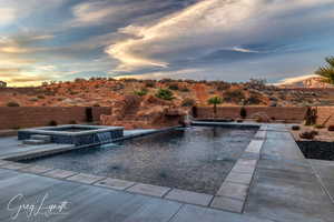 Pool at dusk with an in ground hot tub and pool water feature