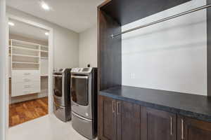 Laundry area featuring light hardwood / wood-style floors and washing machine and clothes dryer