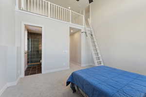 Carpeted bedroom featuring a high ceiling