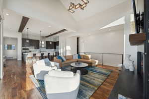 Living room with dark wood-type flooring, sink, beam ceiling, high vaulted ceiling, and a chandelier