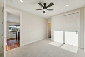 Unfurnished bedroom with light carpet, a closet, and ceiling fan