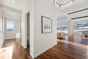 Hallway with beamed ceiling, dark hardwood / wood-style flooring, and an inviting chandelier