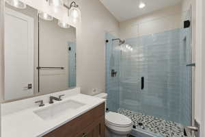 Bathroom with vanity, toilet, and a shower with shower door