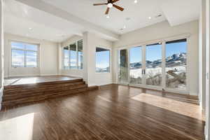 Unfurnished living room featuring a mountain view, ceiling fan, and dark wood-type flooring