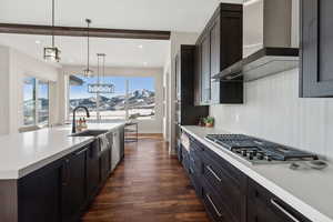 Kitchen featuring beamed ceiling, a mountain view, wall chimney range hood, and a wealth of natural light