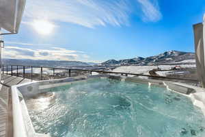 Snow covered pool with a mountain view and a hot tub