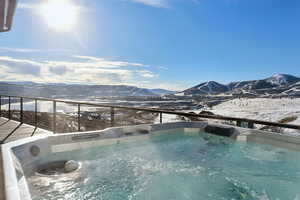 Snow covered pool with a mountain view and a hot tub