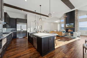 Kitchen with a kitchen breakfast bar, sink, decorative light fixtures, a center island with sink, and built in fridge