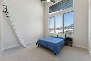 Bedroom with a mountain view, light carpet, ceiling fan, and a high ceiling