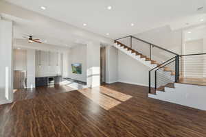 Unfurnished living room with beverage cooler, dark wood-type flooring, and ceiling fan