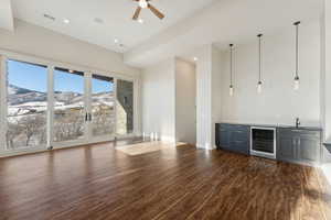 Bar with ceiling fan, dark wood-type flooring, decorative light fixtures, a mountain view, and wine cooler