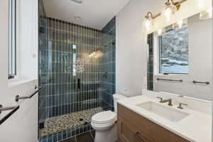 Bathroom featuring tile patterned flooring, vanity, toilet, and an enclosed shower