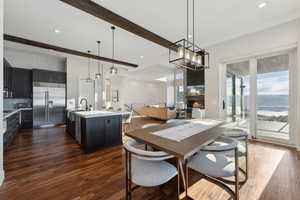 Dining room with a large fireplace, dark hardwood / wood-style flooring, beam ceiling, and sink