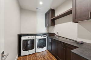 Laundry room with cabinets, dark hardwood / wood-style flooring, and washing machine and clothes dryer