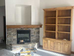 Unfurnished living room featuring a stone fireplace and carpet floors