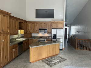 Kitchen with sink, stainless steel appliances, dark stone counters, vaulted ceiling, and light tile patterned floors