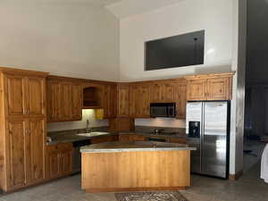 Kitchen with a center island, high vaulted ceiling, light tile patterned floors, and appliances with stainless steel finishes