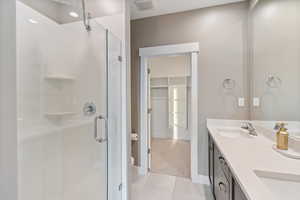 Bathroom featuring tile patterned floors, vanity, and walk in shower