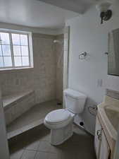 3/4 Bathroom with tile patterned flooring, vanity, toilet, and tiled shower