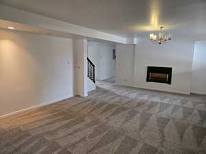 Unfurnished living room featuring carpet floors and an inviting chandelier