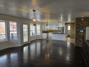 Unfurnished living room featuring a textured ceiling, dark hardwood / wood-style floors, and sink